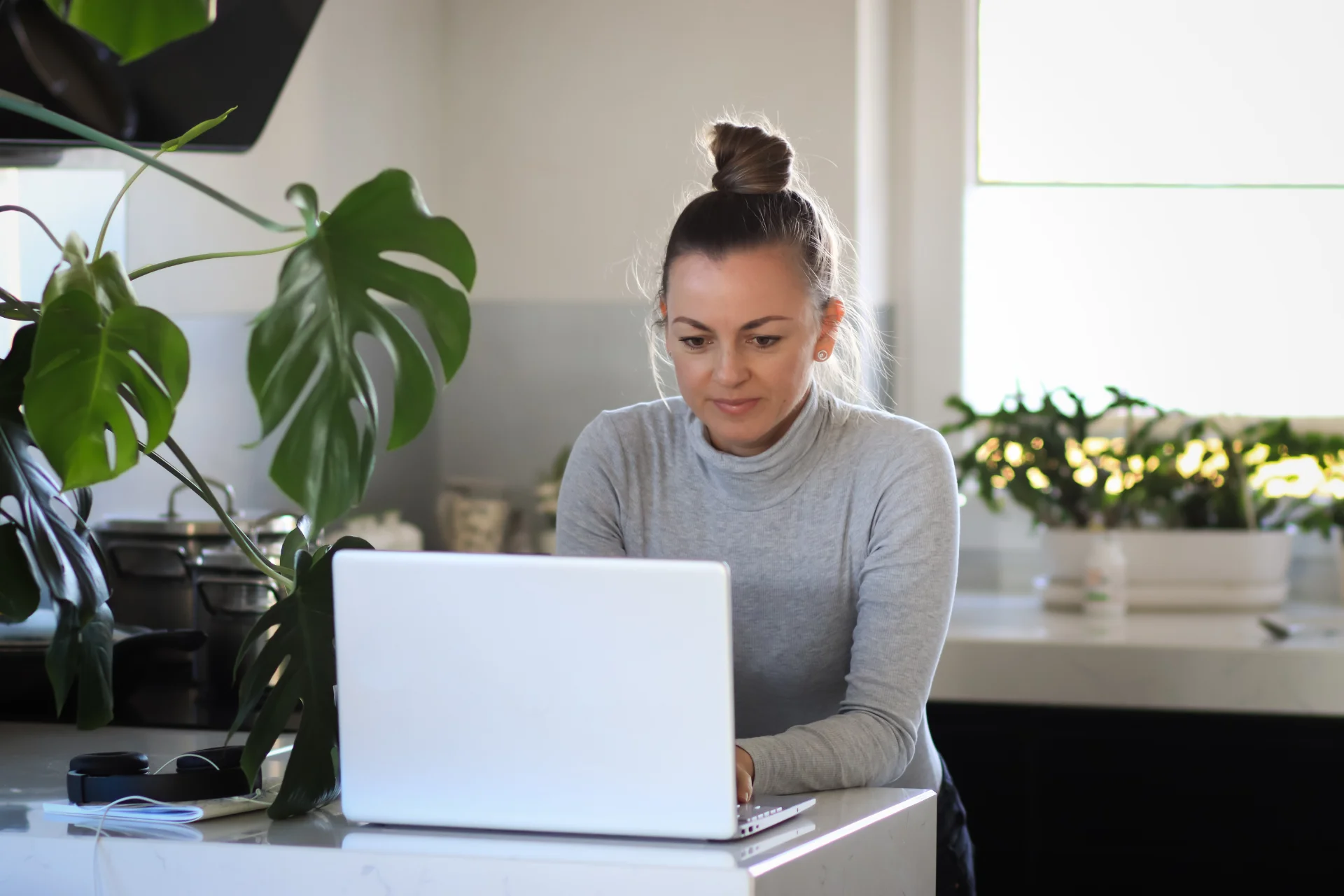 Woman working on laptop at kitchen counter