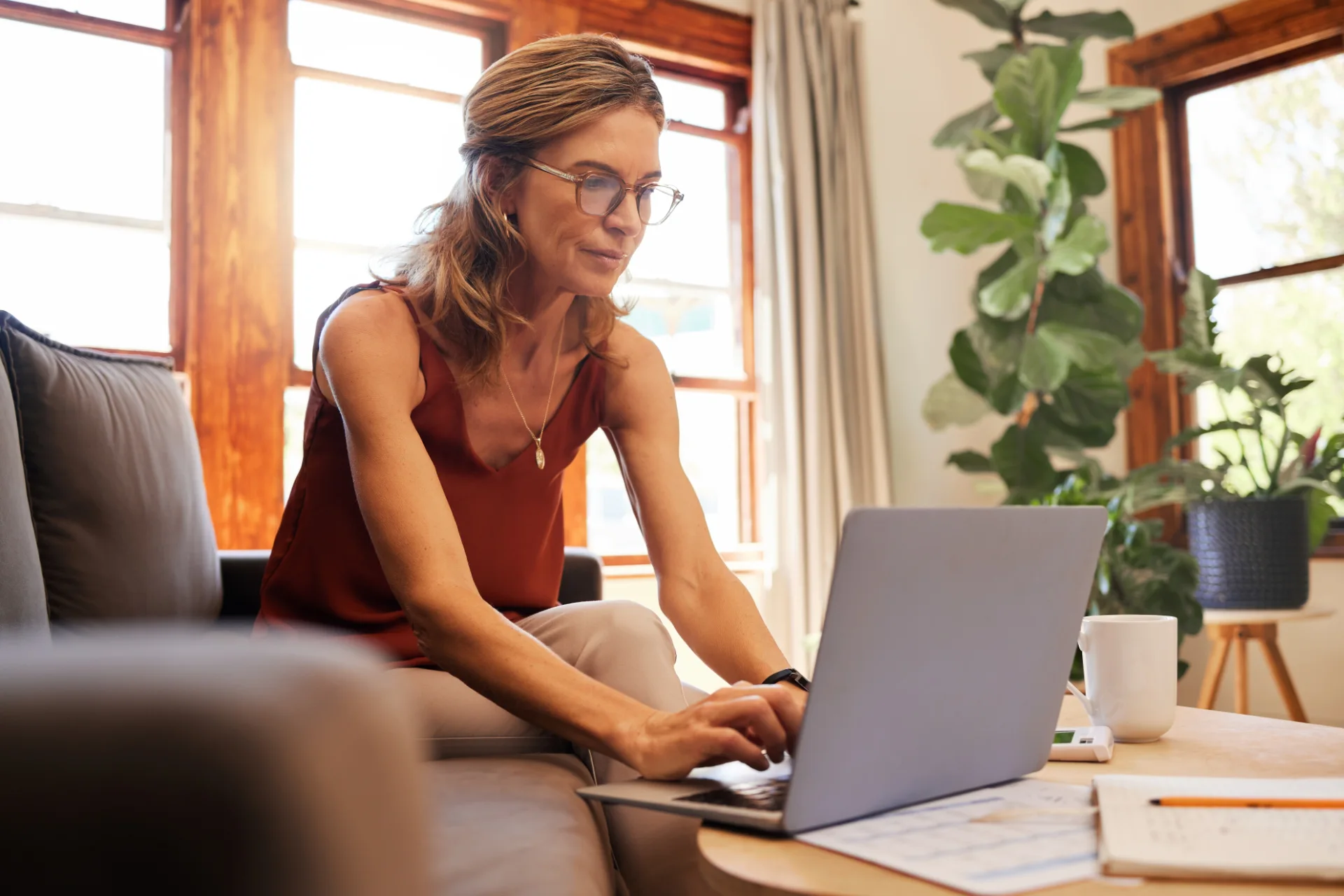 Woman working on a budget at a laptop in a sunlit living room