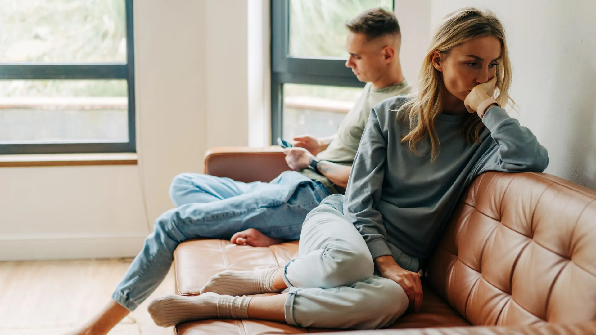 Married couple on couch ignoring each other after a huge fight