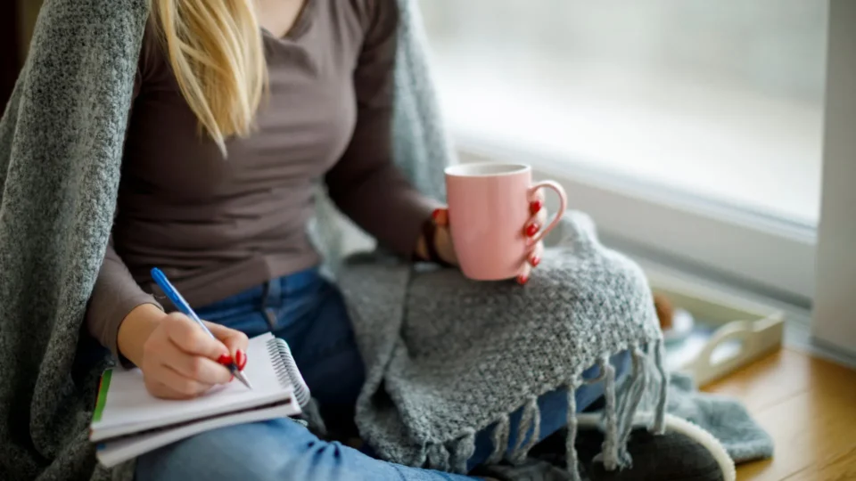 Woman writing a journal in her living room